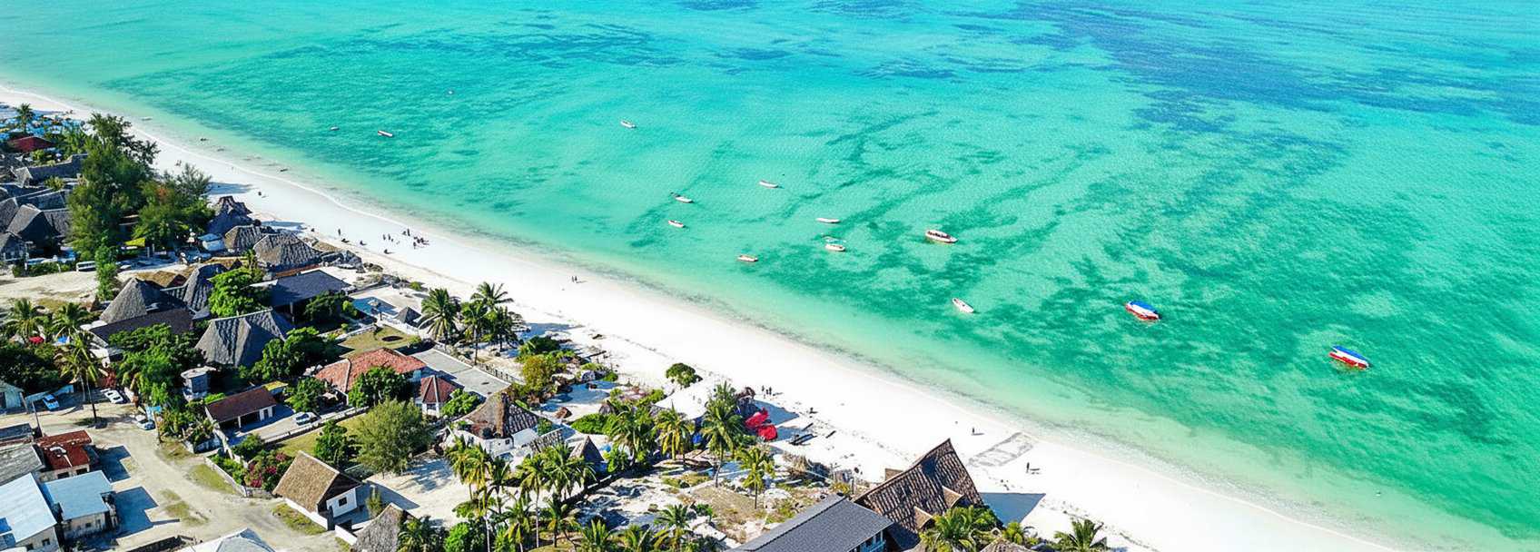Paje beach at low tide - wide stretch of white sand with traditional dhow boats and turquoise water